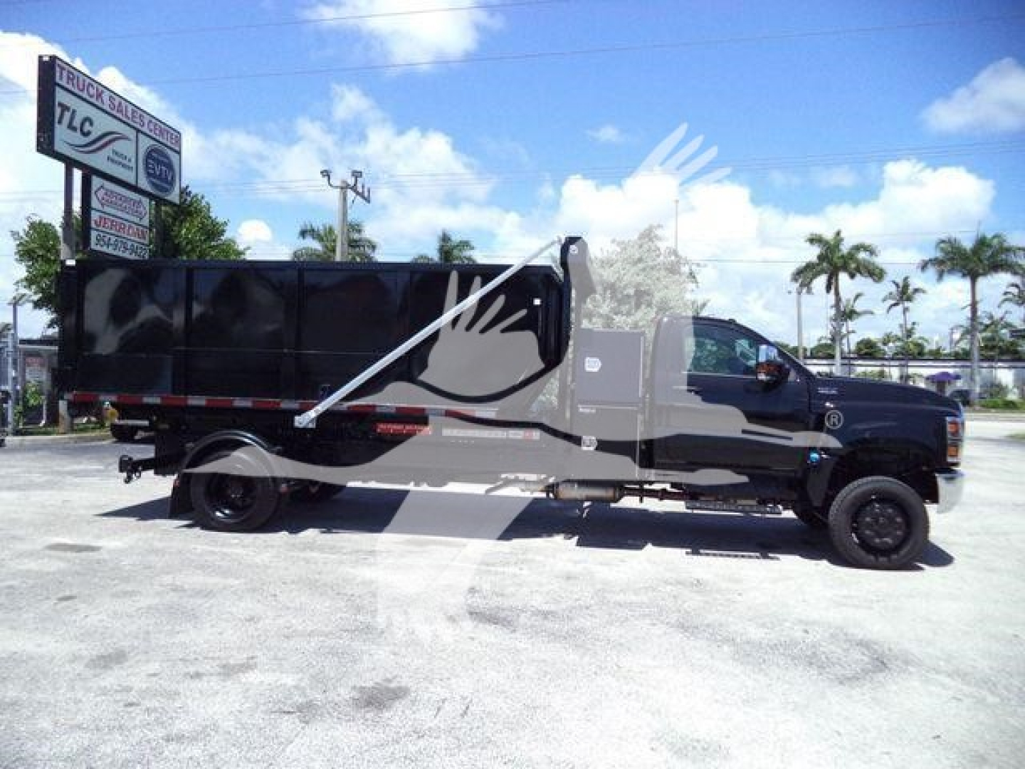 Truck cab and roll-off container on a black/dark gray International CV Series chassis with graphic paint, side view showing dump body.