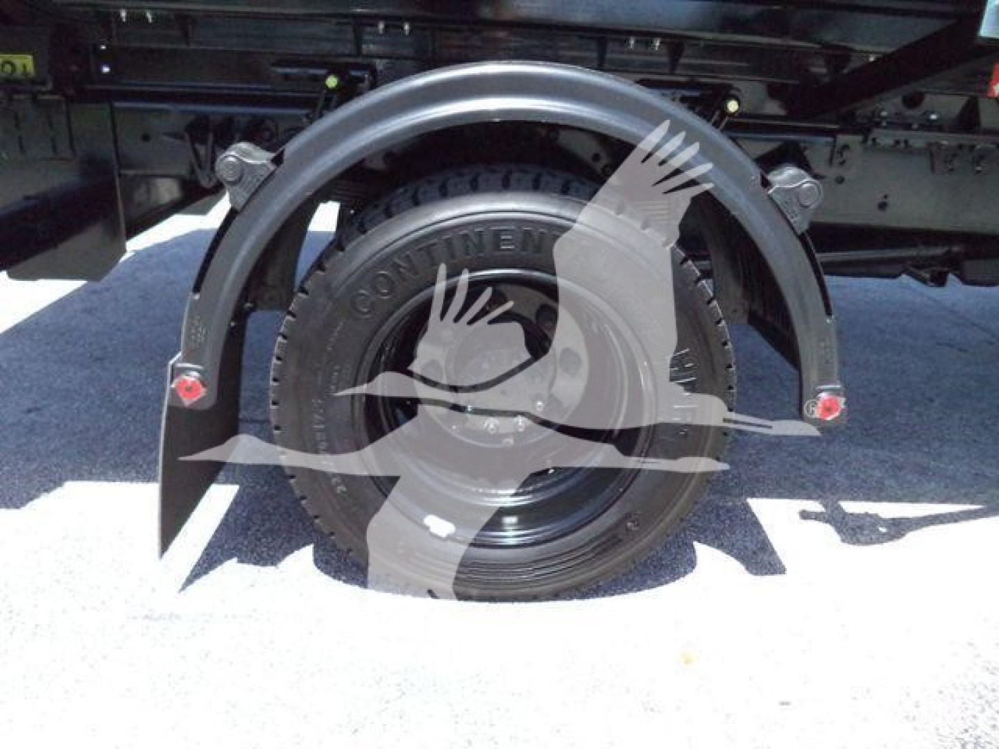 Spare tire mounted on a hoop behind truck with black wheel and fender brackets.