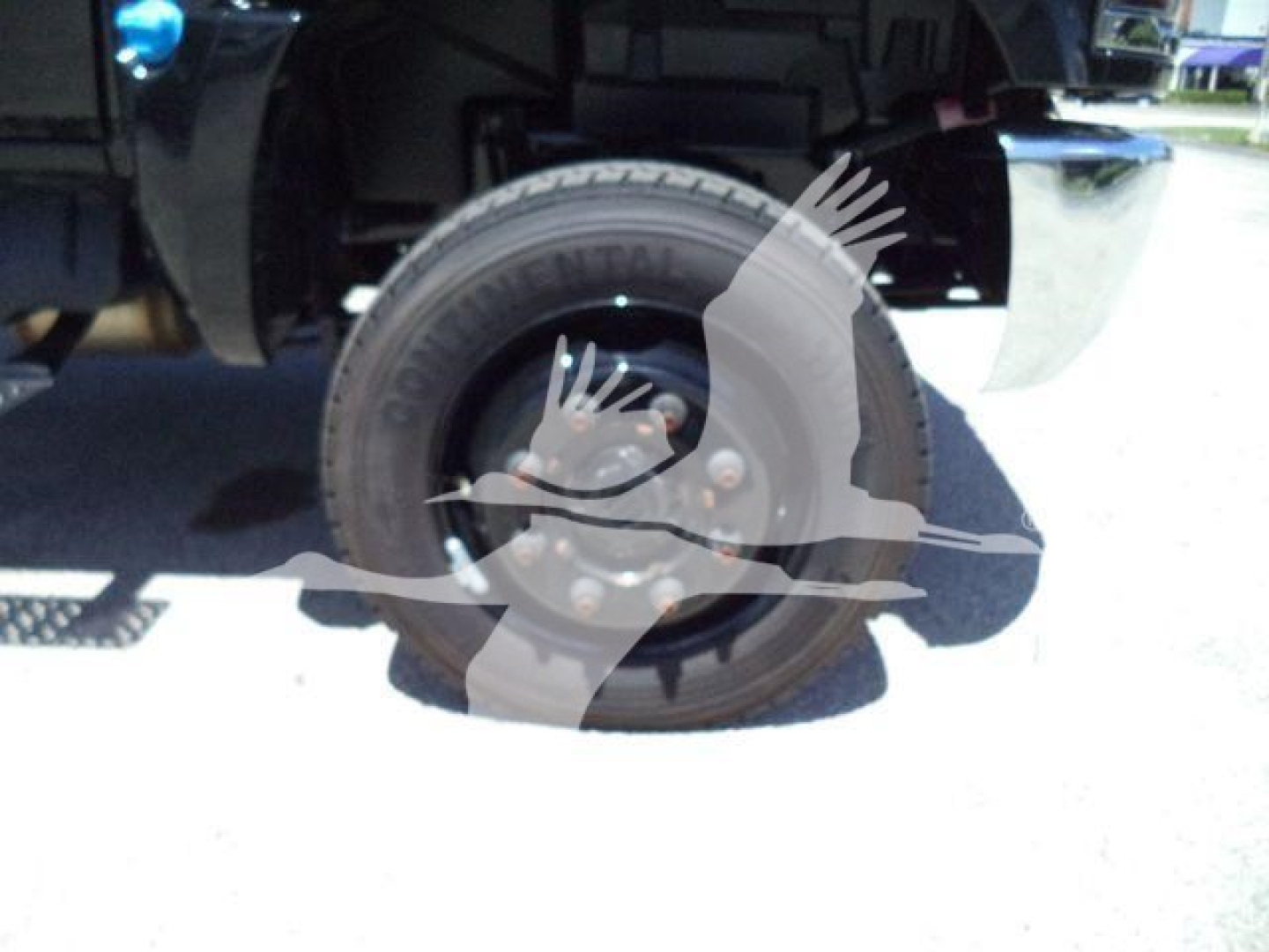 Truck wheel and tire close-up showing Continental tire on solid steel rim under a roll-off truck.