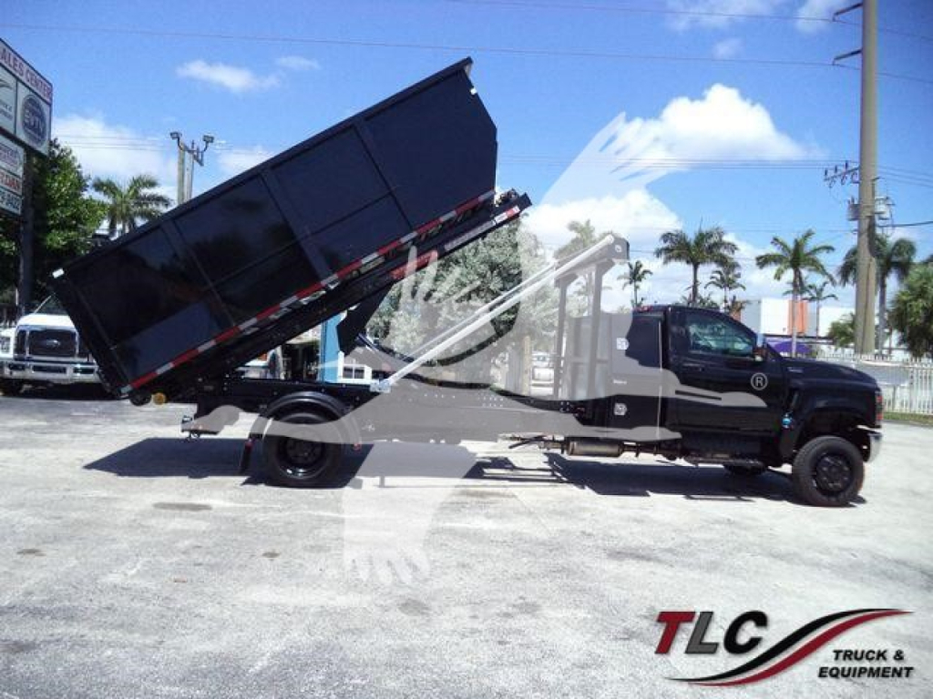 Truck in service with a raised dump bed on a black cab chassis, International CV series, roll-off truck.