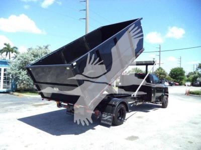 Truck chassis with a raised dump bed in a roll-off configuration showing the tailgate area and rear wheels.