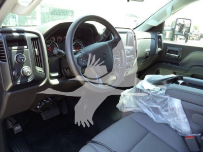 Truck interior showing steering wheel, dashboard, and front seats with protective plastic on the passenger seat; instrument cluster and control panels visible.