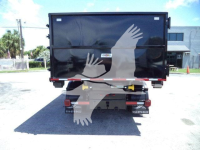 Back view of a black roll-off truck body with a yellow hydraulic component, bumper, and rear lights. faint white silhouettes of hands on the tailgate. No legible serials or labels visible.