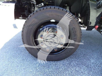 Tire and wheel assembly of a new 2023 International CV roll-off truck showing front wheel with rim and lug nuts.