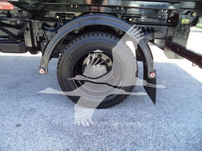 New truck with wheel-well and spare tire visible underframe; partial text on the truck bed and wheel arch; no engine or fluid labels readable.