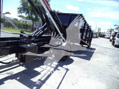 Truck trailer with hydraulic arms and empty cargo bed in a lot showing roll-off truck components.