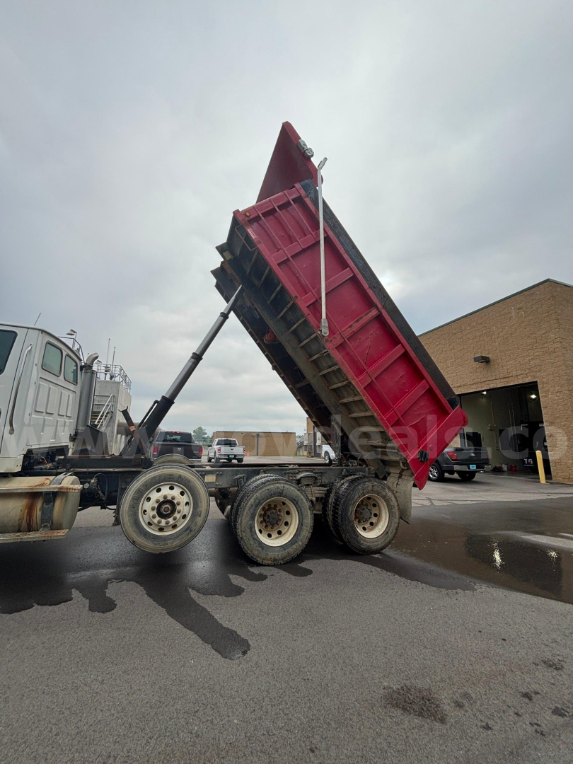 Dump truck in raised bed on a Sterling LT9500 chassis showing hydraulic lift mechanism and red dump body.