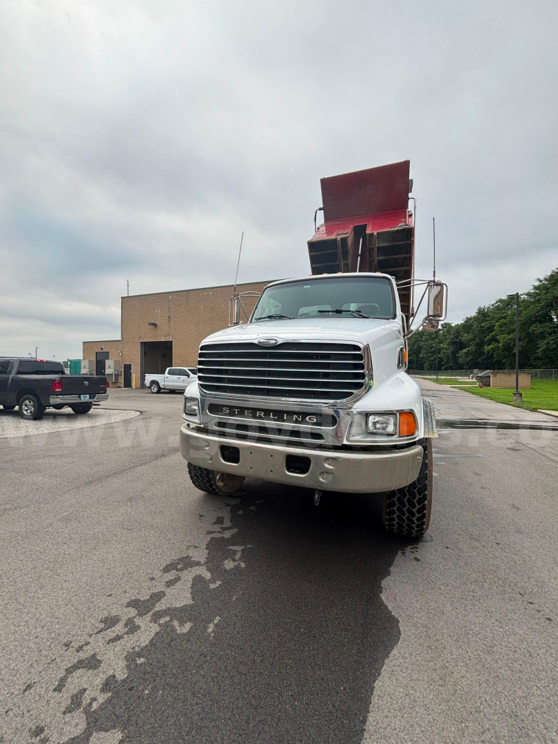 Dump truck front view showing Sterling LT9500 with open-box dump bed raised in a parking lot.
