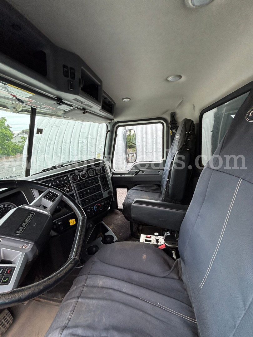 Interior of a 2019 Mack Granite dump truck cab showing steering wheel, dashboard, driver seat, and passenger seat
