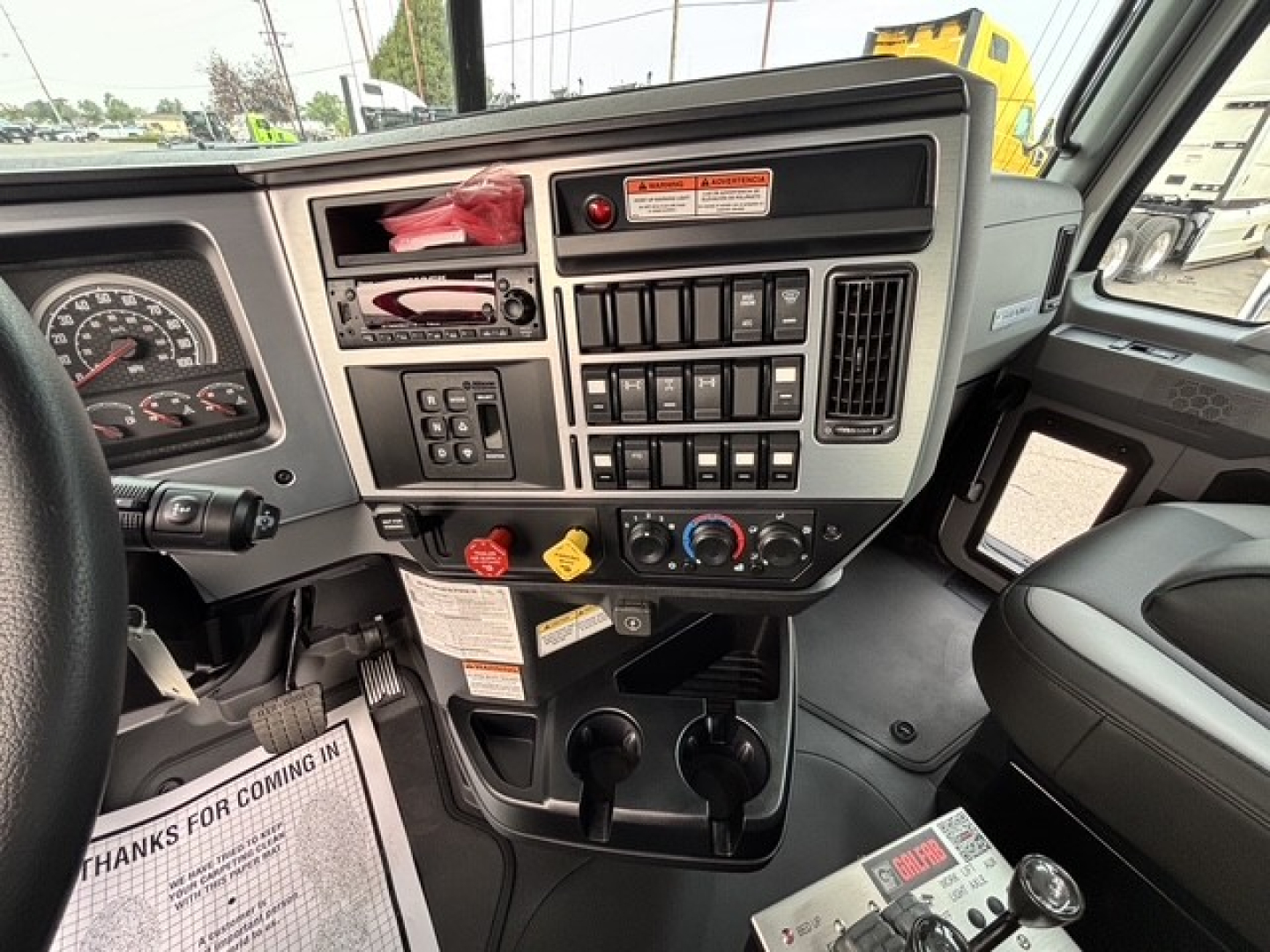 Dashboard and center console of a 2026 Mack GR64B Roll-off truck showing instrument cluster, control panel, climate controls, and cup holders.