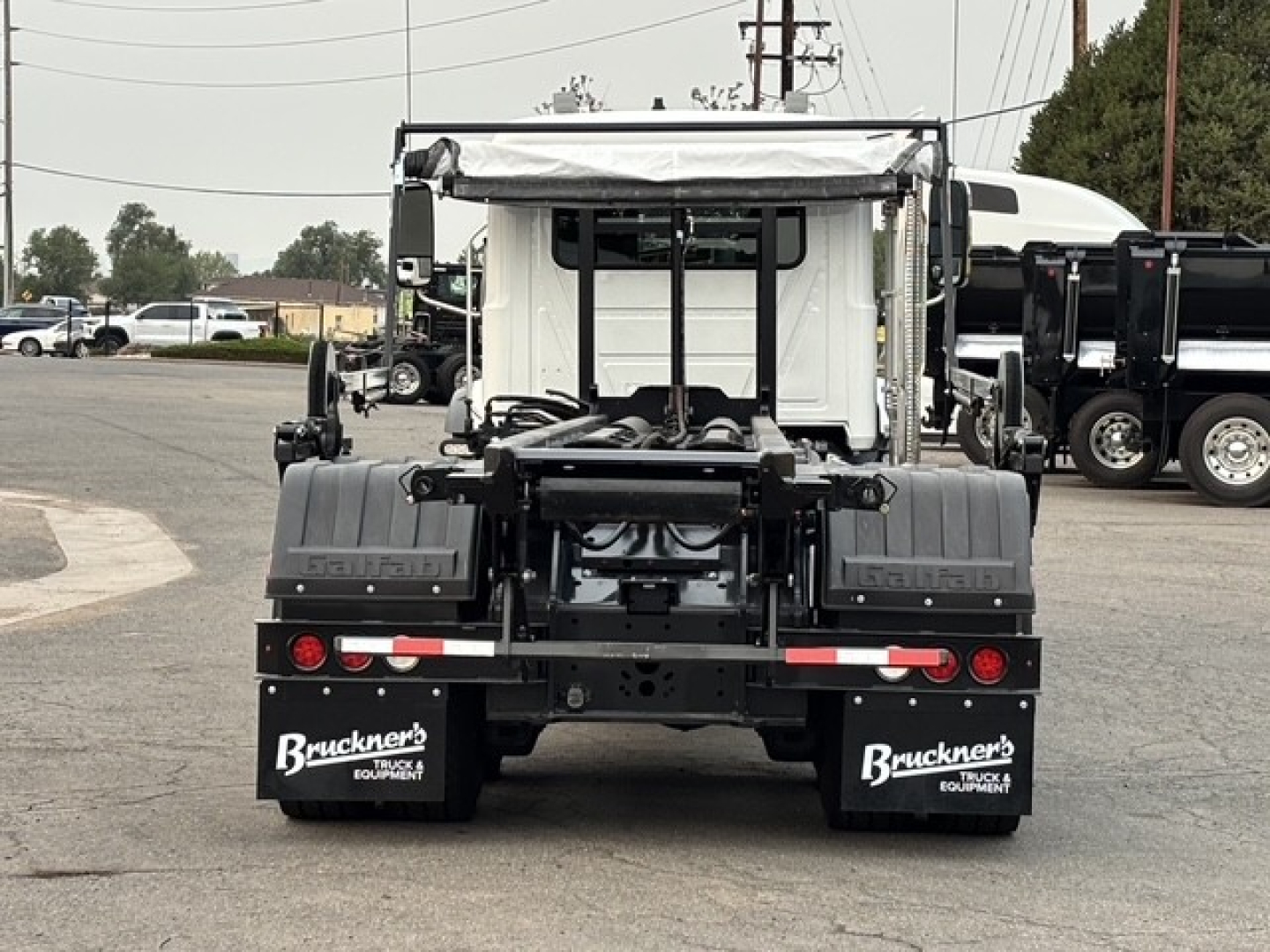 Rear view of a 2026 Mack GR64B roll-off truck showing spare tires, mud flaps with Buckners Equipment branding, and coupling area. VIN and stock not visible.