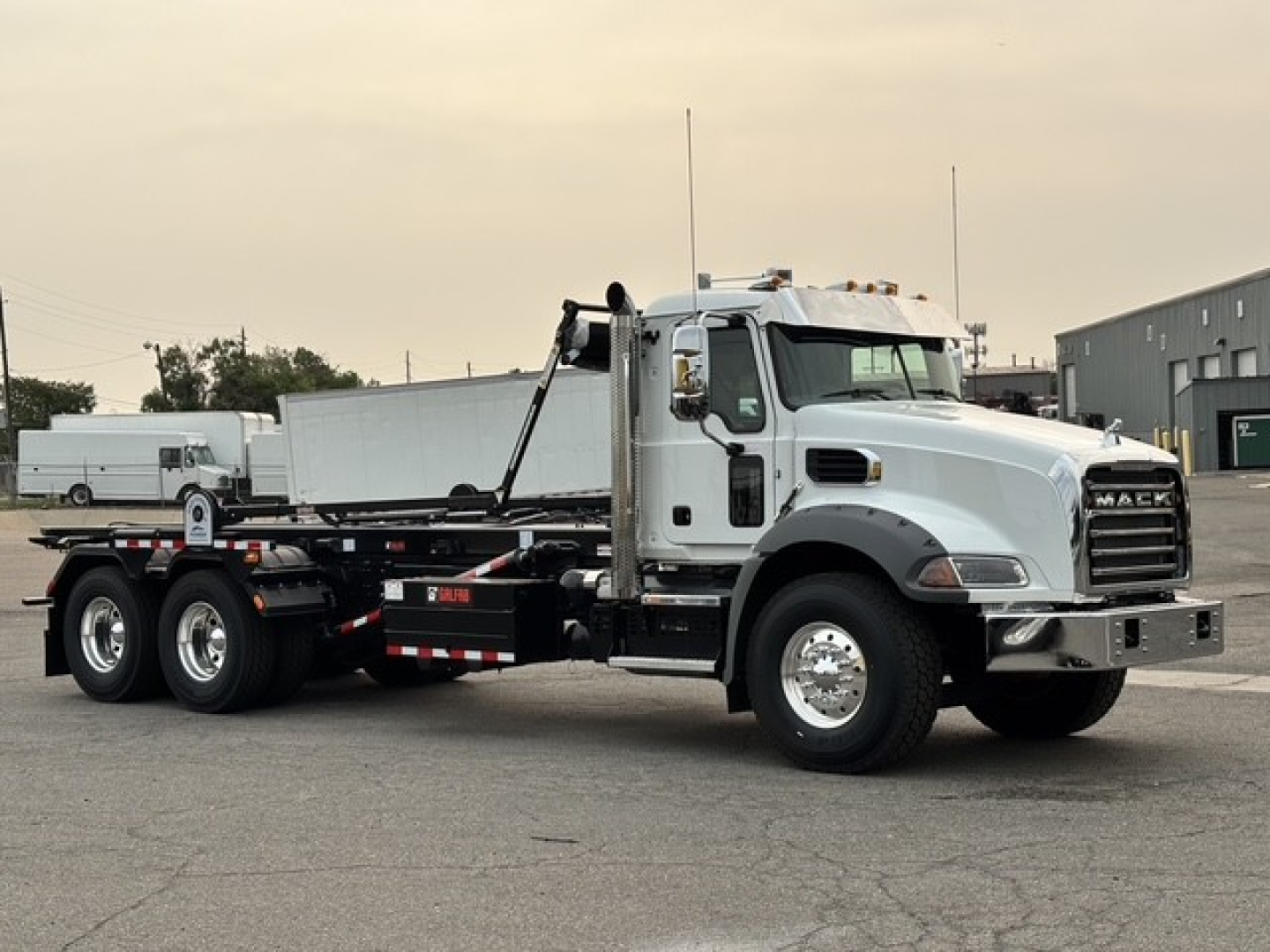 Mack GR64B roll-off truck in showroom stance showing cab front and left side with chassis and wheel axles.