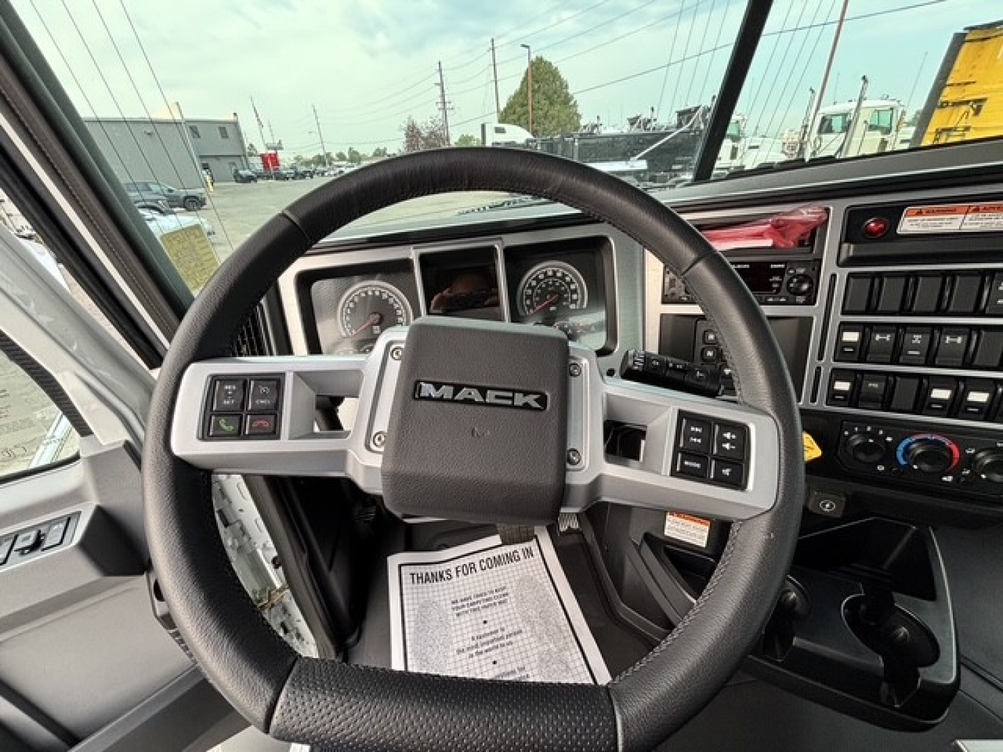 Mack GR64B steering wheel and dashboard in cab showing Mack logo and instrument cluster.