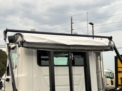 Mack GR64B roll-off truck in new condition showing front cab and cargo cover with hydraulic arms.