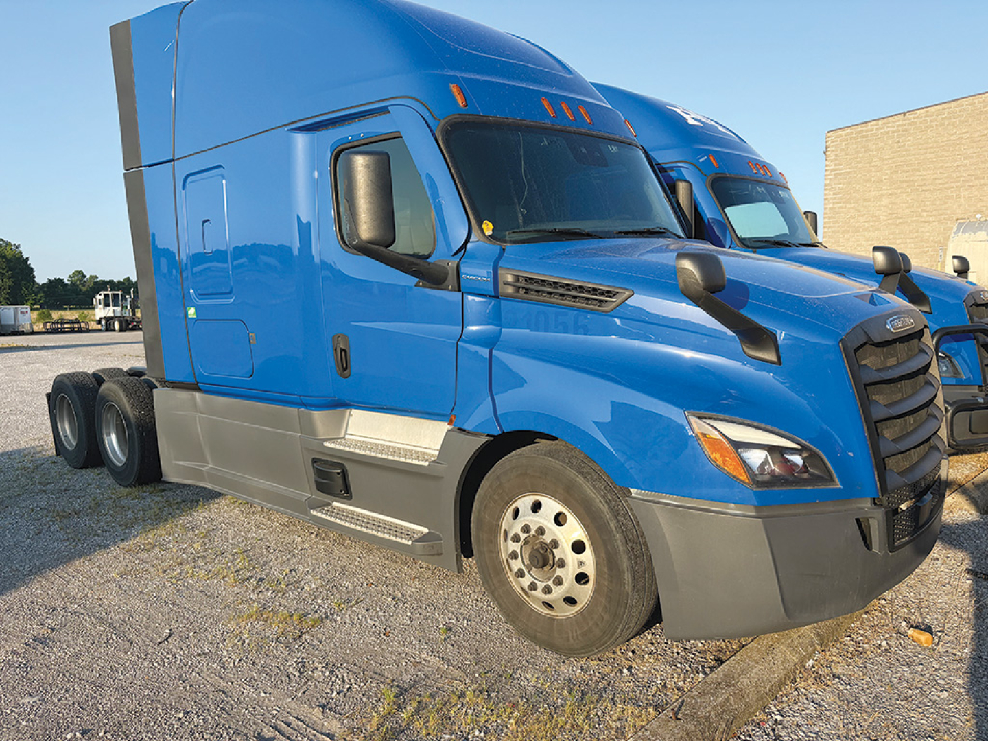 Freightliner Cascadia126 truck in blue side view showing aerodynamic mirrors and aluminum wheels