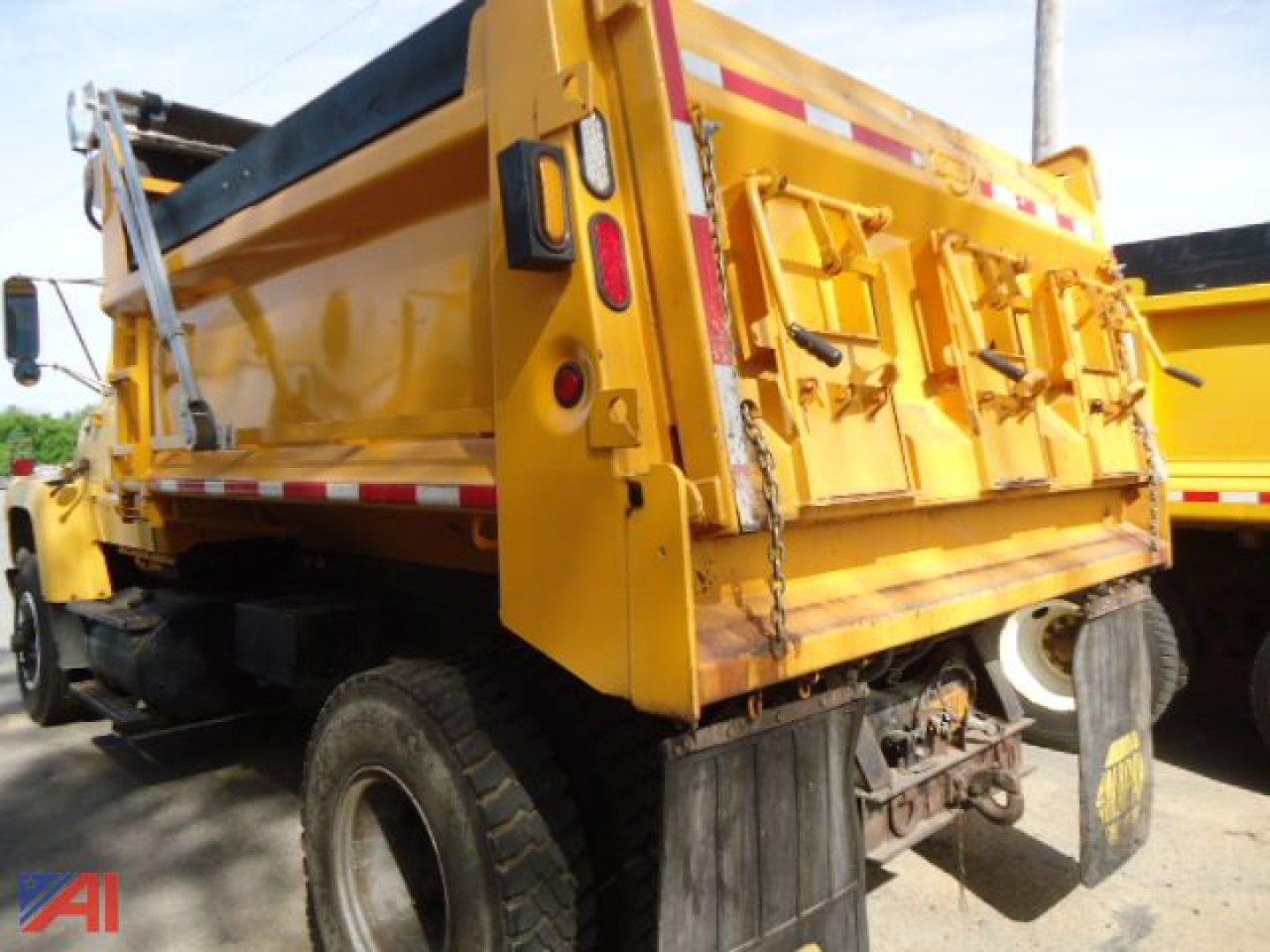 Dump truck bed rear and side view showing bright yellow Ford L8000 dump truck with tailgate and hydraulic system.