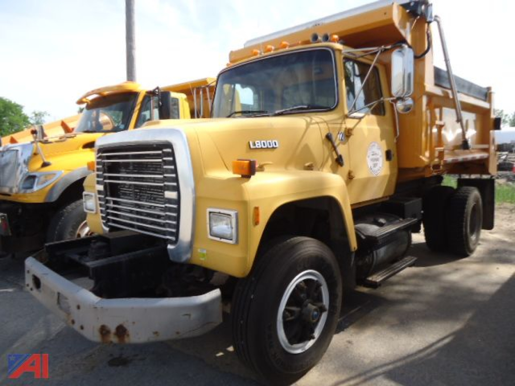 Ford L8000 dump truck in-service showing front grille and cab with L8000 badge, yellow body, and dump bed.