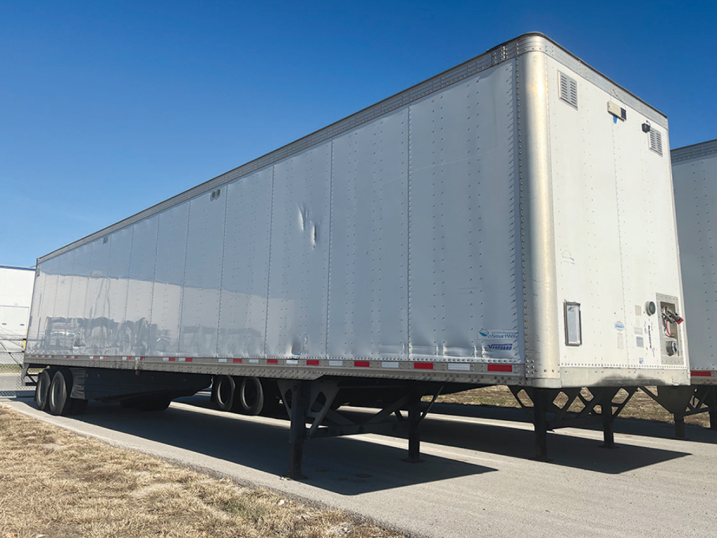 Trailer side view showing Vanguard aluminum dry van with raised roof, tandem axles, rear doors and vee shape at front corner.