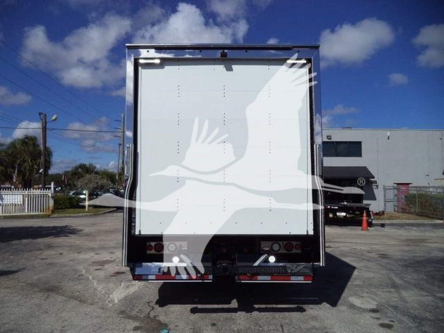 Back of a 2026 Mack MD6 rollback truck trailer, plain white rear doors, reflective tape, and taillights visible.