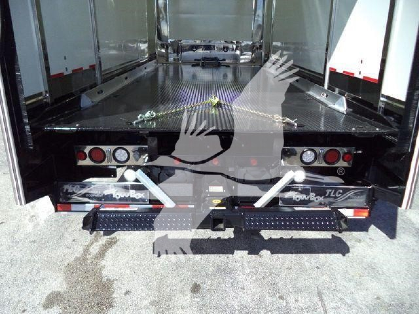 Back of Mack MD6 rollback truck with open cargo area and loading ramps; visible text includes 'Roll Back' and 'TLC' on the bumper, plus small labels and lights.