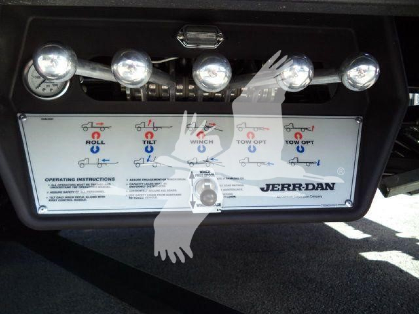 Dashboard panel of a Mack MD6 rollback truck showing control levers and instructional diagram labeled Roll, Tilt, Winch, Tow, with JERR-DAN branding