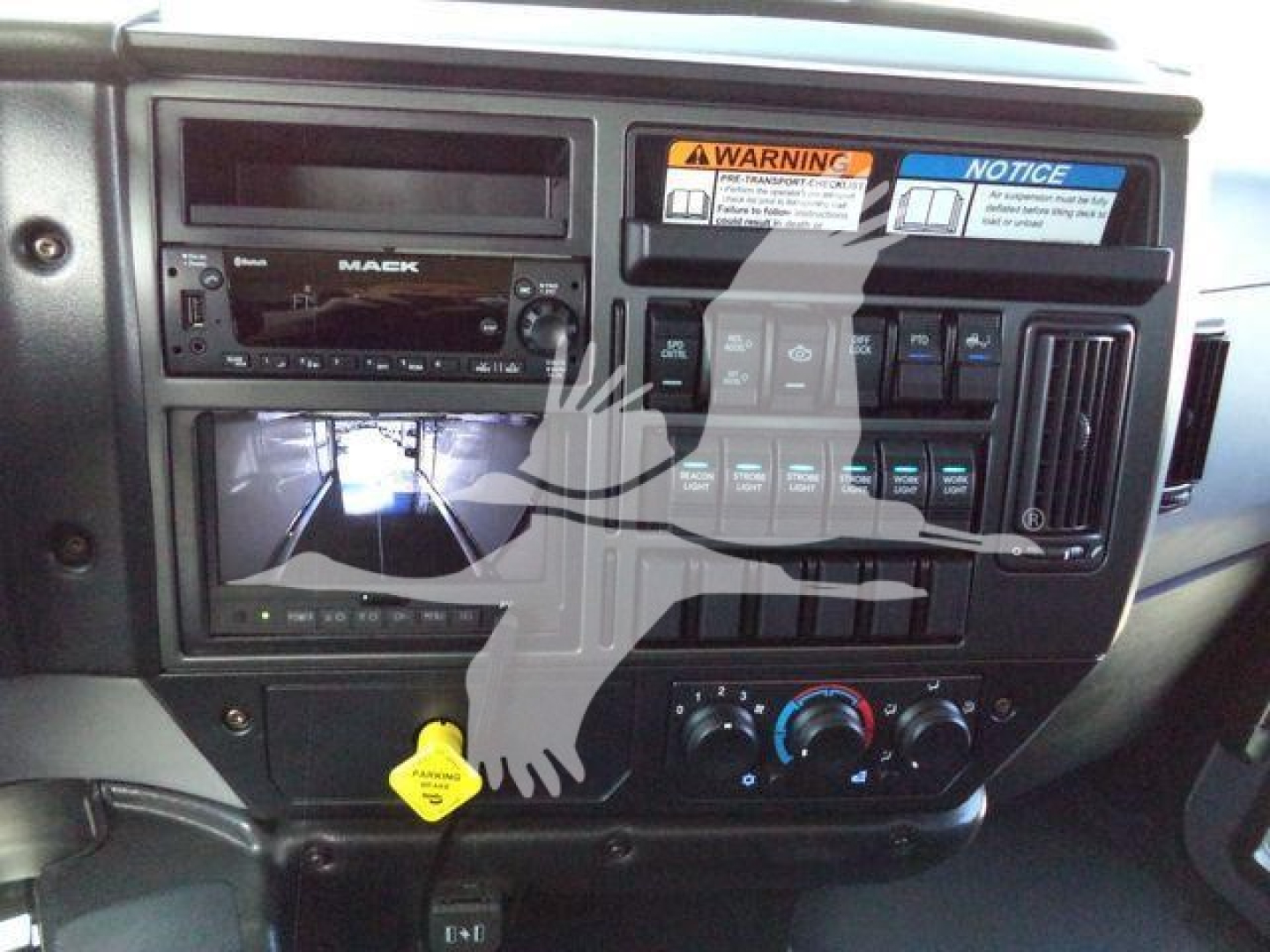 Dashboard area of a 2026 Mack MD6 truck showing instrument cluster, center console with controls, and a yellow tag on a knob.