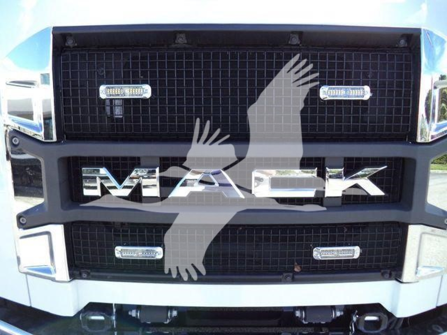 Front grille of a Mack MD6 truck showing the bold 'MACK' badge and chrome grille with two horizontal LED lights on each side, blue cab color visible.