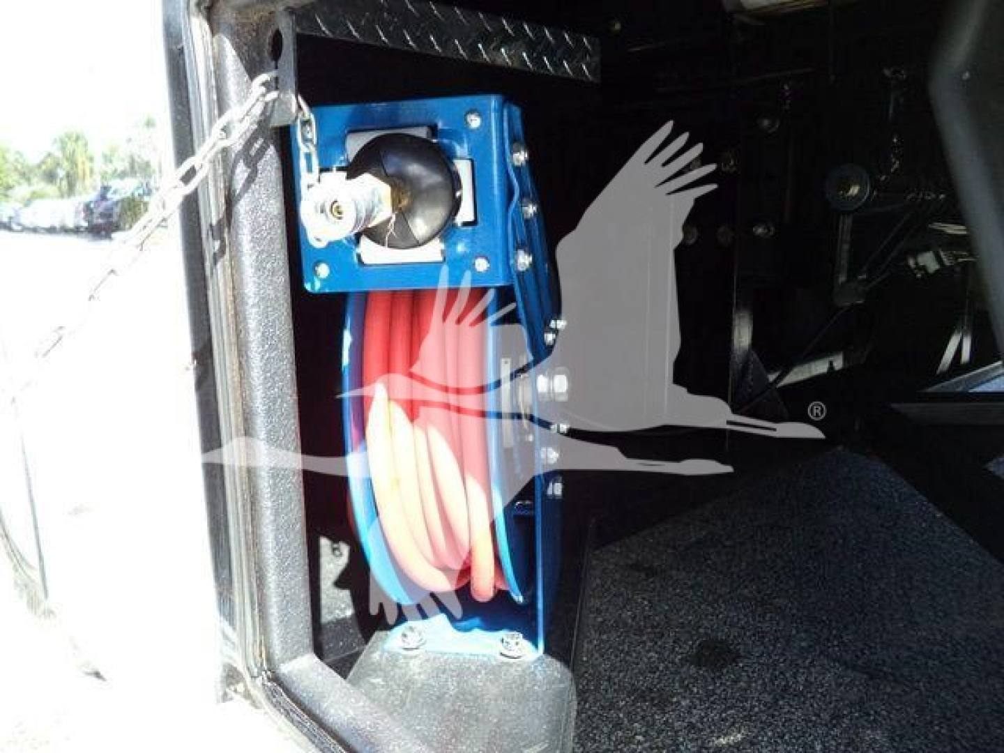 Truck service bay showing a blue hose reel and red reel hose mounted inside a truck bed or tow truck storage area.