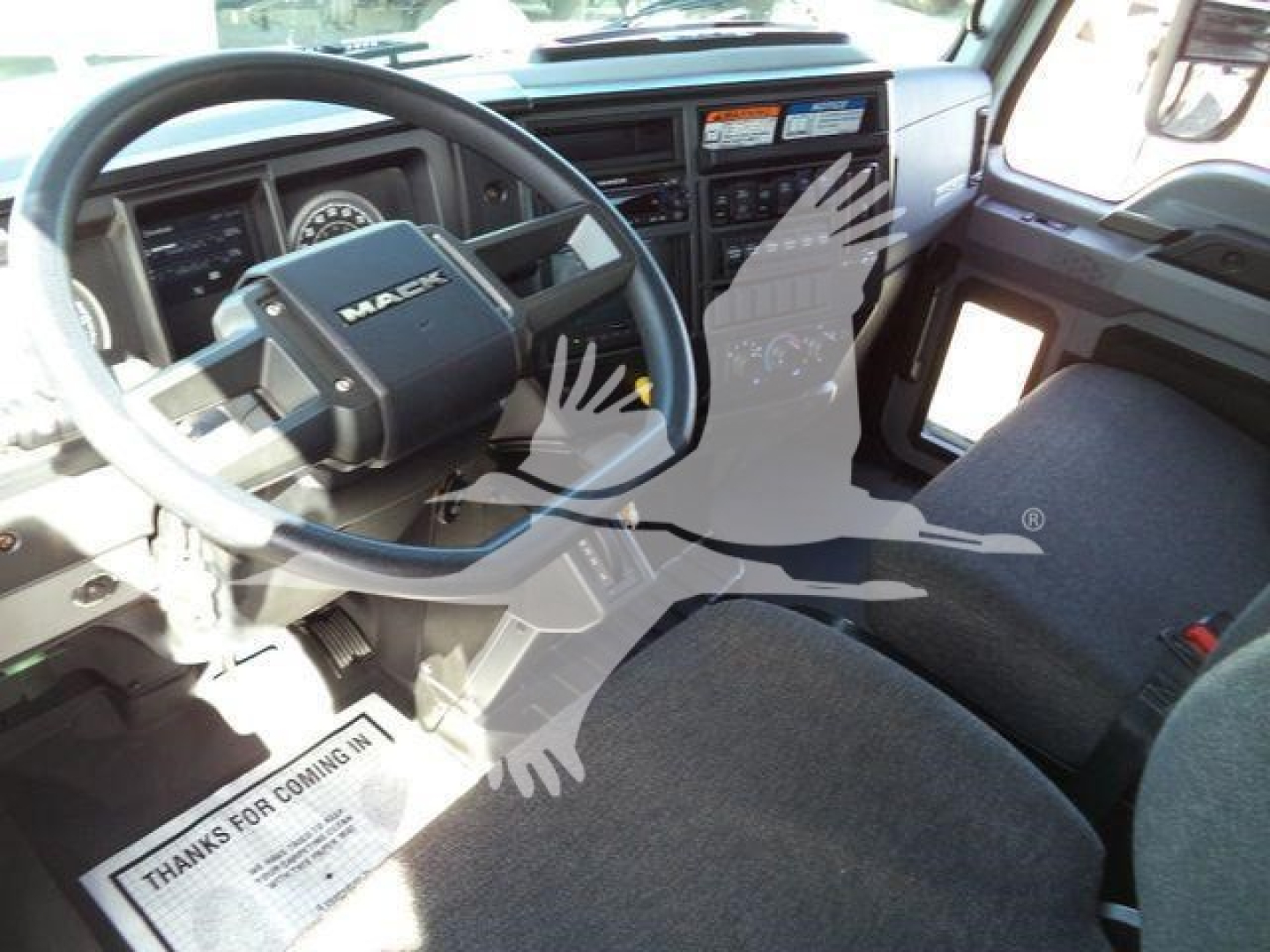 Mack MD6 truck interior showing steering wheel and driver seat with dashboard and controls visible.