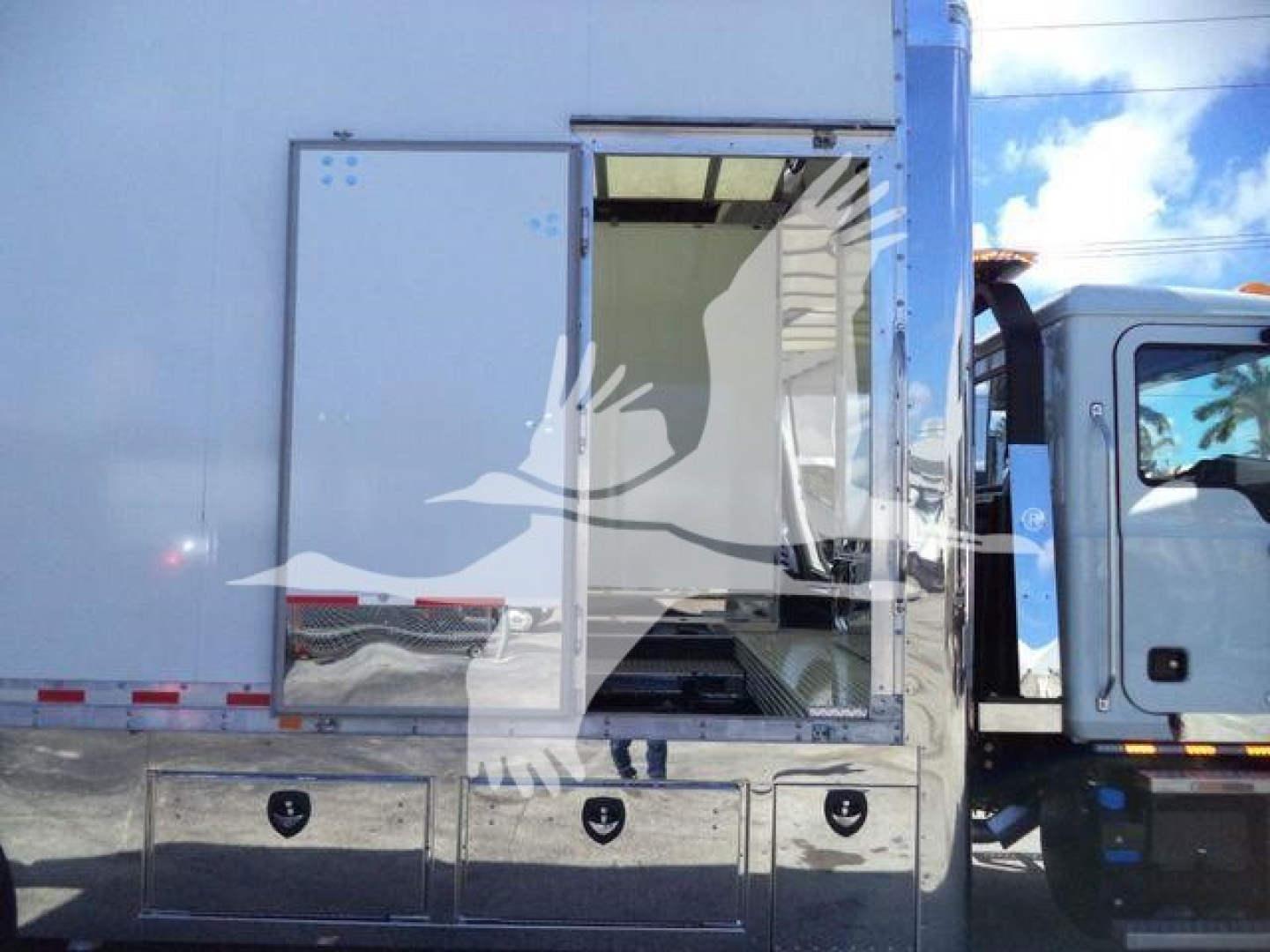 MD6 rollback truck cargo area with side access door open, metal storage drawers visible; noisy urban background.