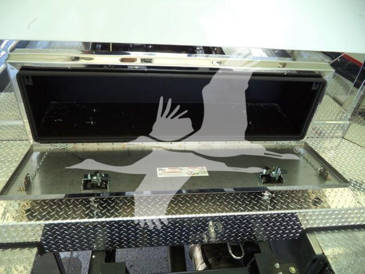 Mack MD6 rollback truck bed storage compartment with open toolbox and diamond plate steel surface.