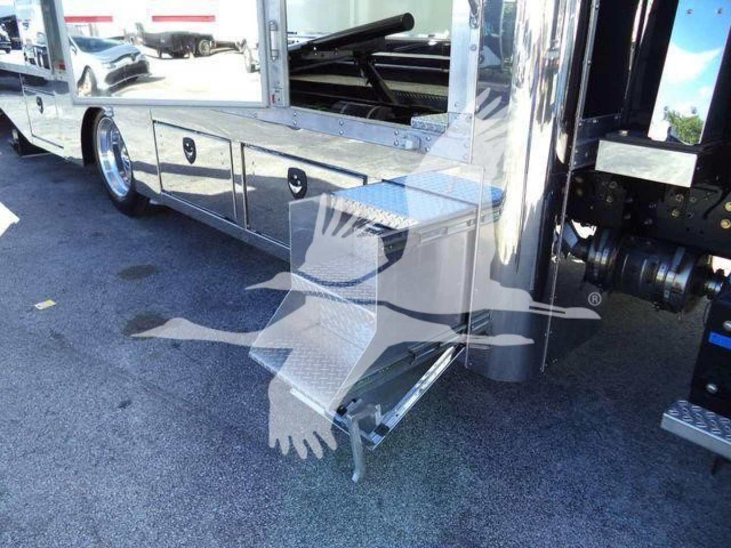 Side view of a 2026 Mack MD6 rollback truck showing a metal step/storage box attached to the side, chrome trim, and polished panels.