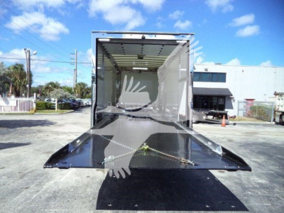 Trucks show a 2026 Mack MD6 rollback truck interior with a flatbed ramp extended, empty cargo area, and rear open cargo bay.