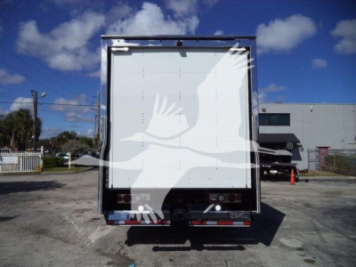 Back of a 2026 Mack MD6 rollback truck trailer, plain white rear doors, reflective tape, and taillights visible.