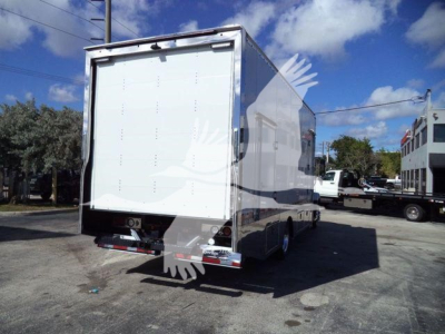 Large white Mack MD6 rollback truck with rear cargo door open, shown from rear-left side.