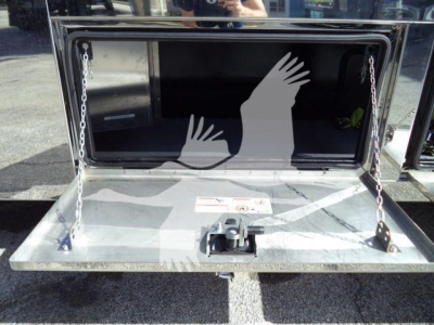 MD6 rollback truck bed with open storage box showing tailgate and support chains, reflective surface in background.
