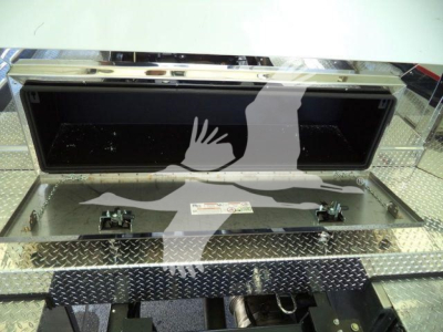 Mack MD6 rollback truck bed storage compartment with open toolbox and diamond plate steel surface.