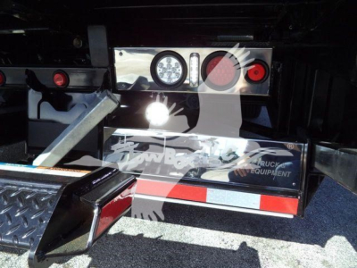 Mack MD6 rollback truck rear showing bumper lights and toolbox with reflective stripes.