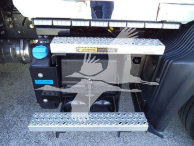 Step/footboard area of a Mack MD6 truck showing diamond plate running boards and a blue reservoir cap.