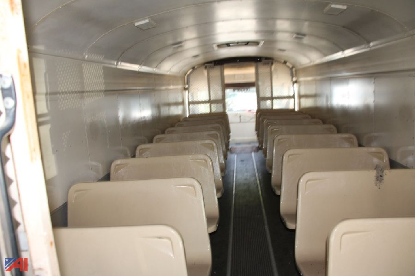 Bus interior showing seating arrangement in a 1995 Blue Bird TC2000 school bus converted layout with tan seats and narrow aisle.