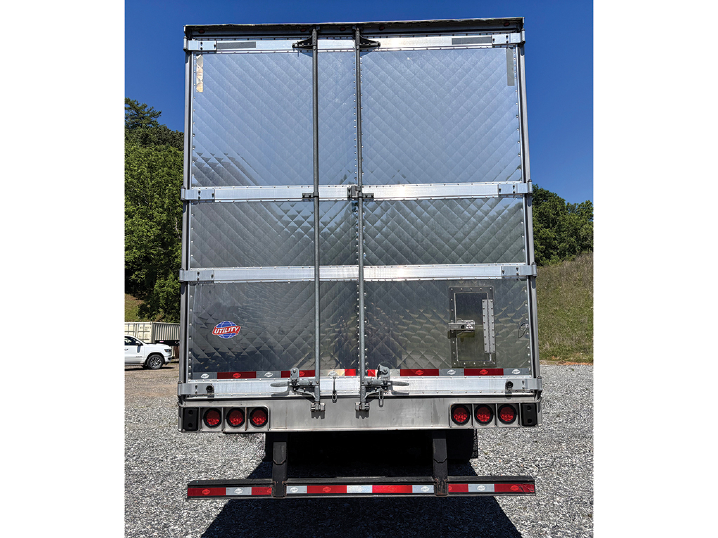 Utility 3000R trailer rear view showing diamond plate aluminum doors and rear bumper with lights.