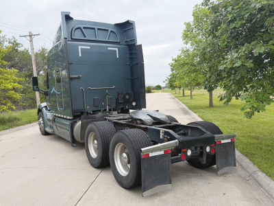 Peterbilt 579 UltraCab tractor rear view showing fifth wheel, dual rear axles, and mud flaps with a dark teal body.