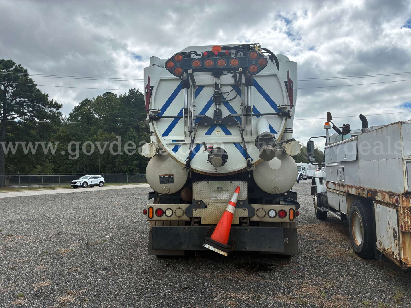 Truck rear view of a Freightliner M2 106 vacuum service vehicle with large water tank, hoses, safety cones, and rear-mounted equipment.