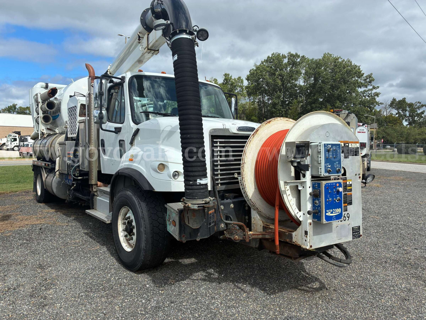 Freightliner M2 106 vacuum truck side view with hose reel and front cab visible.