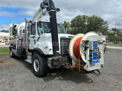 Freightliner M2 106 vacuum truck side view with hose reel and front cab visible.