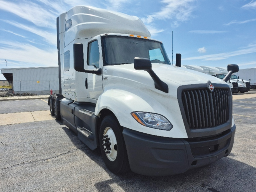 International LT625 conventional sleeper truck in white, front-left view, with large black grille, dual mirrors, and side steps.