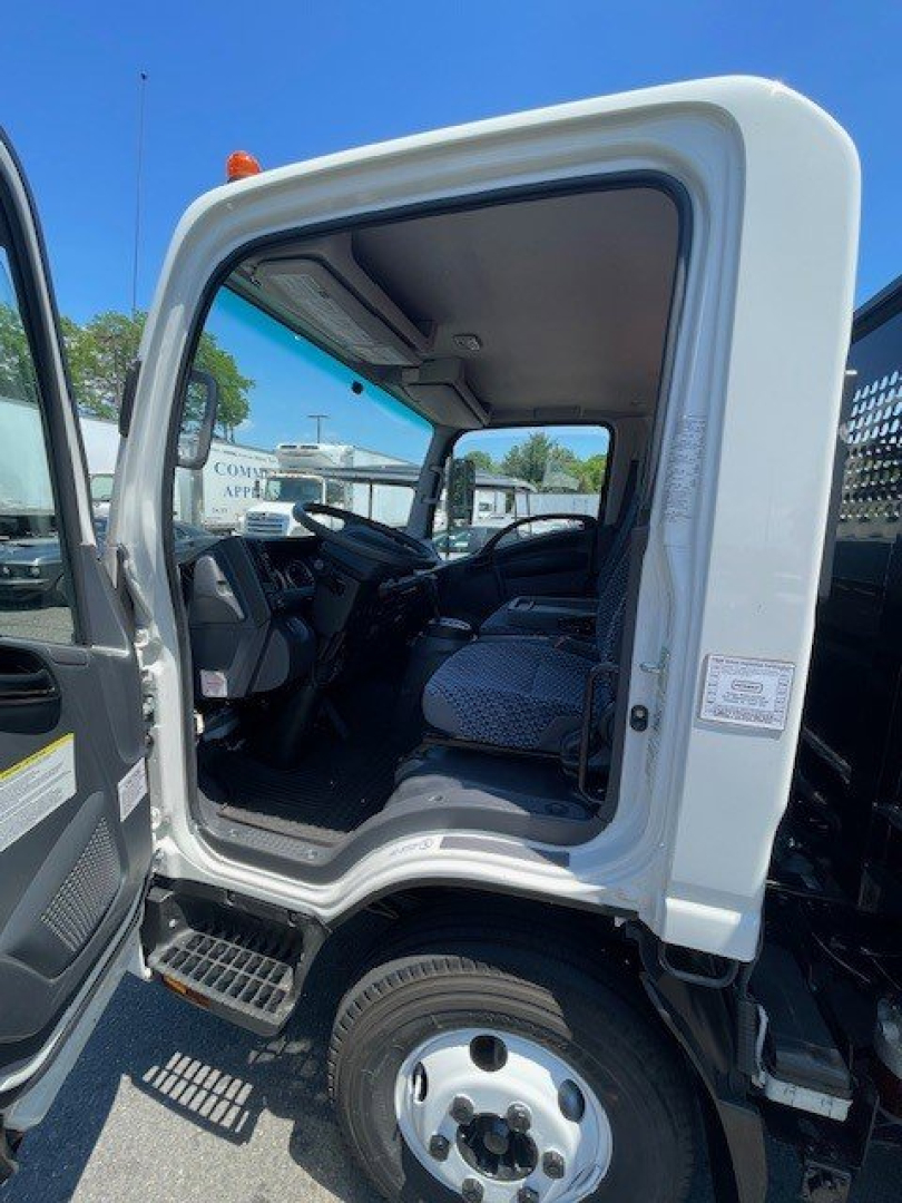 Isuzu NPR HD truck cab interior viewed from open driver door with seating and dashboard visible.