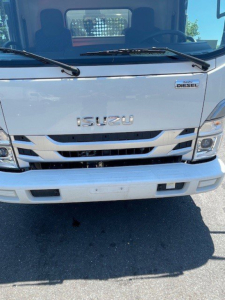Isuzu NPR HD truck front view showing ISUZU emblem, diesel badge, grille, headlights, and bumper.