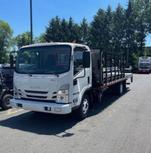 Isuzu NPR HD box truck with white cab, black flatbed cargo area, front grille showing Isuzu emblem. Visible text on front: likely 'ISUZU' and model details; no legible stickers or serials seen.