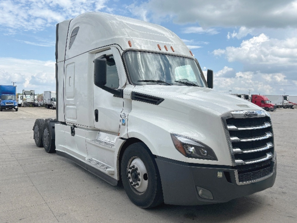 Freightliner Cascadia126 sleeper tractor in a parking lot, white exterior with black front bumper, three axles with dual rear wheels, VIN plate area not visible.